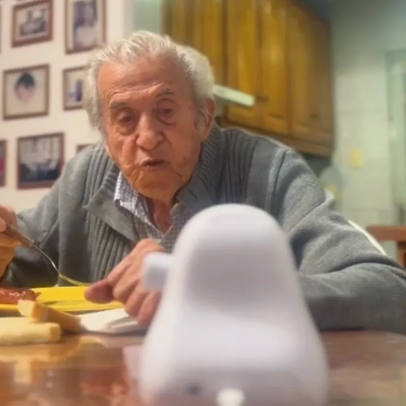 Carlos seated at a table with Ato in the foreground