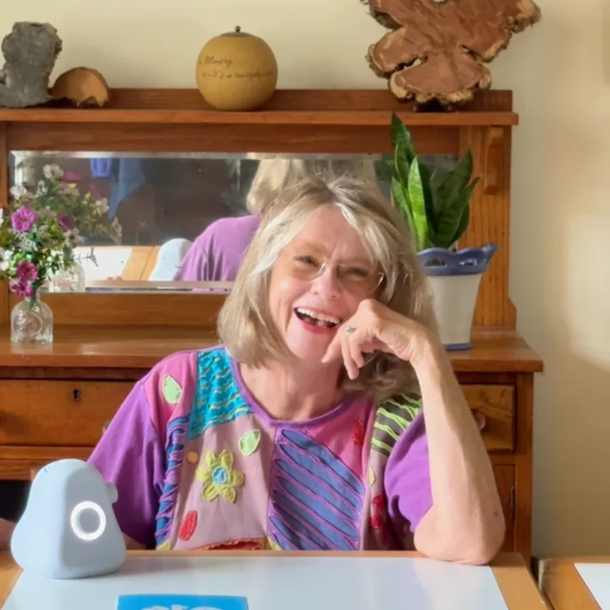 Libby seated at home with Ato on the table beside her